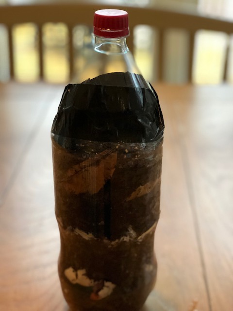 plastic liter bottle full of soil with top taped on