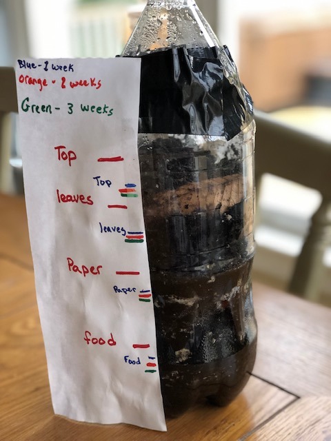 paper marking experiment tracking for week 3 taped to plastic bottle full of soil